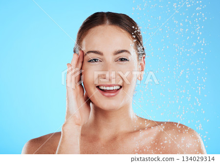 Shower, water and portrait of happy woman in a studio face from cleaning and skincare. Wellness, splash and beauty routine of female model excited from dermatology and self care with blue background Shower, water and portrait of happy woman in a studio face from cleaning and skincare. Wellness, splash and beauty routine of female model excited from dermatology and self care with blue background 134029314