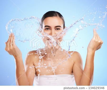 Water splash, portrait or girl with face wash for skincare, fresh body hygiene on blue background in studio. Female model with clean hands or wellness washing in beauty grooming for facial treatment 134029346