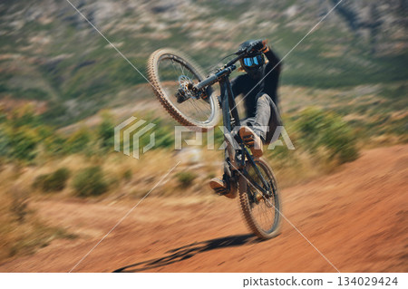 Cycling, training and person on a bicycle in the countryside for extreme sport, adrenaline and fun. Speed, action and cyclist on a dirt road for stunt, trick or fitness, freedom and balance in nature 134029424