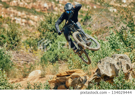 Action, sports and mountain bike with man jumping in nature for cycling, fitness and adventure. Adrenaline junkie, performance and stunt with athlete riding outdoors for energy, risk and training Action, sports and mountain bike with man jumping in nature for cycling, fitness and adventure. Adrenaline junkie, performance and stunt with athlete riding outdoors for energy, risk and training 134029444