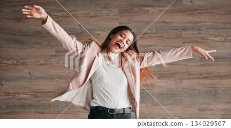 Freedom, dance and happy with woman on wall background for crazy, celebration and confidence. Winner, pride and music with young female and dancing in studio for happiness, energy and carefree 134029507