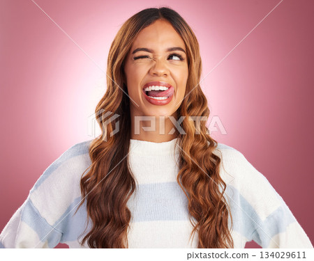 Funny, face and goofy woman tongue out feeling happy, playful and excited isolated in a studio purple background. Comic, joke and head of a young and crazy female wink for humor or happiness 134029611