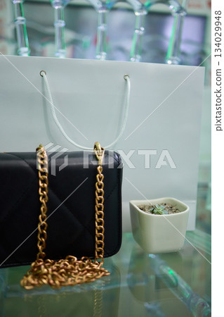 Refined evening handbag presented on sleek glass platform with gentle illumination, Sophisticated purses highlighted with subtle shadows and polished high end ambiance Refined evening handbag presented on sleek glass platform with gentle illumination, Sophisticated purses highlighted with subtle shadows and polished high end ambiance 134029948