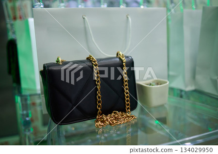 Refined evening handbag presented on sleek glass platform with gentle illumination, Sophisticated purses highlighted with subtle shadows and polished high end ambiance Refined evening handbag presented on sleek glass platform with gentle illumination, Sophisticated purses highlighted with subtle shadows and polished high end ambiance 134029950