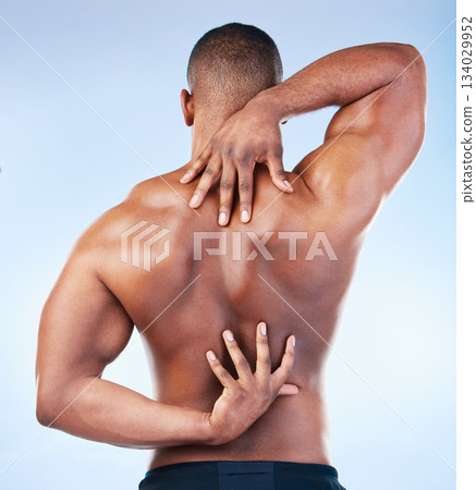 Back, strong and black man with muscle touching his spine as self love, skincare and isolated in a studio blue background. Health, wellness and strong muscular male model embracing skin 134029952