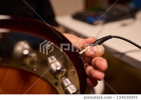 Musician setting up equipment, Preparing bass guitar for recording, Electric bass player organizing gear in studio, Closeup of musician tuning and adjusting bass instrument Musician setting up equipment, Preparing bass guitar for recording, Electric bass player organizing gear in studio, Closeup of musician tuning and adjusting bass instrument 134030045