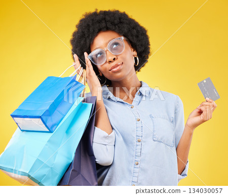 Shopping bag, retail thinking or black woman with credit card for sales product, fashion deal or mall store present. Commerce market, gift idea or customer contemplating isolated on yellow background Shopping bag, retail thinking or black woman with credit card for sales product, fashion deal or mall store present. Commerce market, gift idea or customer contemplating isolated on yellow background 134030057