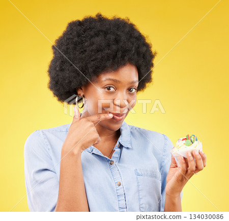 Black woman, cupcake and studio portrait for smile, temptation or cheat with junk food by yellow background. African model, cake of diet choice for health, nutrition or sweets with decision for meal Black woman, cupcake and studio portrait for smile, temptation or cheat with junk food by yellow background. African model, cake of diet choice for health, nutrition or sweets with decision for meal 134030086
