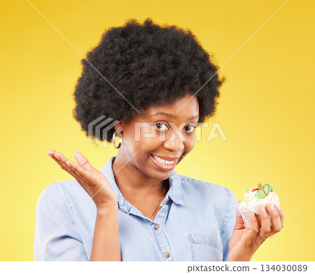 Young black woman, cupcake dessert and studio with temptation, cheat diet and junk food by yellow background. African model, cake and choice for unhealthy, nutrition and sweets with meal in portrait 134030089