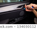 Mechanic fixing vehicle door parts, Closeup of technician repairing car interior components, Professional worker servicing vehicle door with detailed focus and tools 134030112