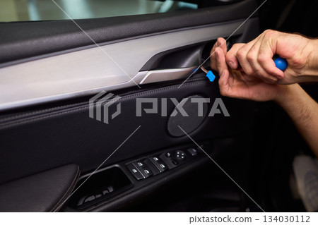 Mechanic fixing vehicle door parts, Closeup of technician repairing car interior components, Professional worker servicing vehicle door with detailed focus and tools 134030112