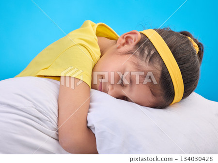 Calm young girl, pillow and sleep in a studio feeling tired, fatigue and ready for dreaming. Isolated, blue background and happy little child with pillows and closed eyes for sleeping, rest and nap Calm young girl, pillow and sleep in a studio feeling tired, fatigue and ready for dreaming. Isolated, blue background and happy little child with pillows and closed eyes for sleeping, rest and nap 134030428