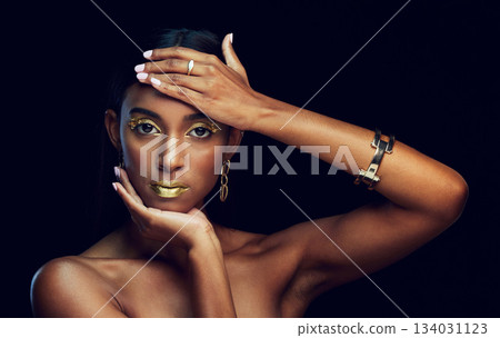 Woman, face and beauty with gold makeup, fashion and art with hand frame and elegance on dark background. Style, skin and luxury with jewelry, serious female in portrait and creative in studio 134031123
