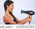 Happy woman singing, hair care or dryer in studio for healthy natural shine, beauty or wellness. Funny Indian girl model, salon tools or self care equipment in grooming routine on white background 134031244