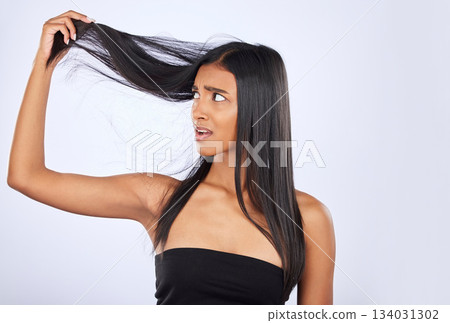 Hair damage, breakage and shock of a frustrated woman isolated on a white background in studio. Bad, unhappy and an Indian girl sad about split ends, holding tangled hairstyle and frizzy haircare Hair damage, breakage and shock of a frustrated woman isolated on a white background in studio. Bad, unhappy and an Indian girl sad about split ends, holding tangled hairstyle and frizzy haircare 134031302