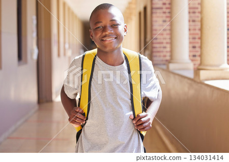 Student, child and backpack standing in school campus lobby for study. Back to school portrait, African boy and ready for education, learning or knowledge with happy smile in high school building 134031414