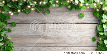 Lush green ivy leaves frame rustic wooden background adorned with soft glowing lights creating warm and inviting atmosphere perfect for festive christmas celebration 134031652