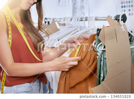 Fashion, tape measure and clothes designer woman measuring clothing or fabric in workshop. Creative, startup planning or textile manufacture of female small business owner in studio working on dress. Fashion, tape measure and clothes designer woman measuring clothing or fabric in workshop. Creative, startup planning or textile manufacture of female small business owner in studio working on dress. 134031828