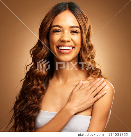 Hair care, beauty and woman with smile in portrait, balayage and keratin treatment on brown background. Happy female, curly hairstyle and cosmetics, cosmetology in studio with makeup, skin and shine 134031865