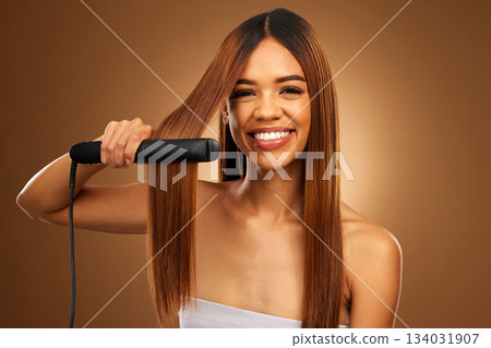 Hair care, portrait of woman with hot iron and smile for luxury salon treatment on brown background. Beauty, haircut and happy hispanic model with straight hairstyle in studio for haircare styling. 134031907