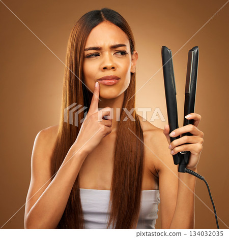 Hair, thinking and woman with flat iron for beauty, wellness and keratin treatment on brown background. Hairdresser mockup, salon and confused girl for healthy growth, haircare texture and cosmetics 134032035