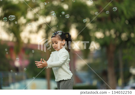 happy toddler girl running and playing soap bubble in park happy toddler girl running and playing soap bubble in park 134032250