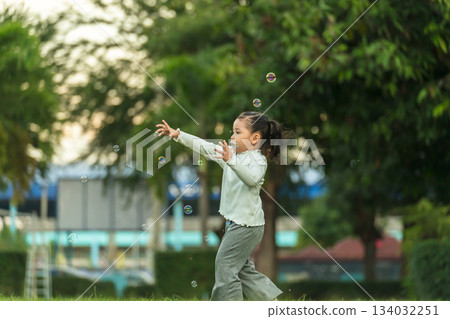 happy toddler girl running and playing soap bubble in park happy toddler girl running and playing soap bubble in park 134032251