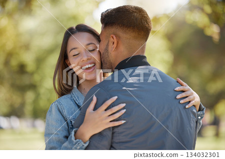 Couple, outdoor and kiss on cheek with a smile for love, care and happiness together in summer. Young man and woman at nature park for affection or hug on happy and romantic date or vacation to relax 134032301