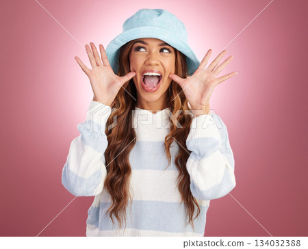 Excited, comic hands and face of woman on studio background for funny, humour and emoji reaction. Beauty, fashion and happy girl model with facial expression in trendy style, cosmetics and casual hat 134032388