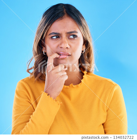 Thinking, doubt and worry with a woman on a blue background in studio feeling unsure or uncertain. Idea, confused and problem solving with a young female looking for a solution or asking a question Thinking, doubt and worry with a woman on a blue background in studio feeling unsure or uncertain. Idea, confused and problem solving with a young female looking for a solution or asking a question 134032722