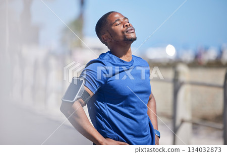 Fitness, training and tired man runner outdoors for break from exercise, cardio or running on blurred background. Workout, stop and breathe by athletic male outside for marathon, run or sport routine 134032873