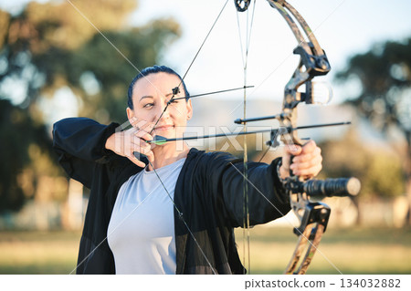 Woman, bow or arrows aim in sports field, shooting range or gaming ground for hunting, hobby or performance exercise. Person, archery or athlete and weapon in target training, competition or practice Woman, bow or arrows aim in sports field, shooting range or gaming ground for hunting, hobby or performance exercise. Person, archery or athlete and weapon in target training, competition or practice 134032882