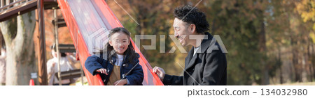 秋葉掩映下的公園裡，父母和孩子們在溜滑梯上玩耍。 134032980