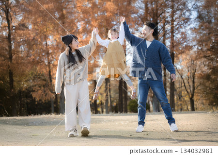 Family playing in autumn park. Jumping high and holding hands, an image of going out and leisure. Family playing in autumn park. Jumping high and holding hands, an image of going out and leisure. 134032981