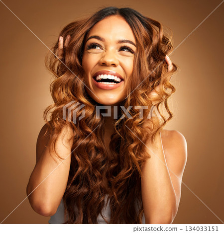 Thinking, hair and excitement with a model woman on a brown background in studio for natural haircare. Idea, salon and shampoo with an attractive young female feeling excited by keratin treatment 134033151
