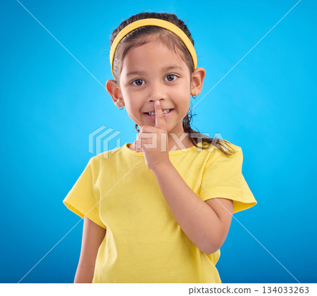 Young girl secret, portrait and studio with a student feeling happy with blue background. Isolated, cute and adorable child face in a yellow outfit with happiness, whisper and cheerful from gossip Young girl secret, portrait and studio with a student feeling happy with blue background. Isolated, cute and adorable child face in a yellow outfit with happiness, whisper and cheerful from gossip 134033263