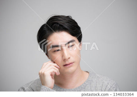 Close-up of a man looking down and thinking with a gray bag 134033364