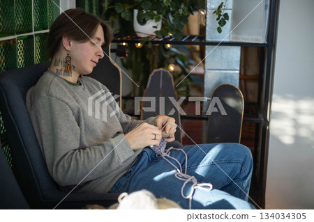 Hipster feminine male crochet handmade knitting hobby with colored yarn and hook at wooden interior Hipster feminine male crochet handmade knitting hobby with colored yarn and hook at wooden interior 134034305