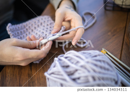 Man hands crochets handmade crocheting supplies assorted wool yarn hook knitting top view closeup Man hands crochets handmade crocheting supplies assorted wool yarn hook knitting top view closeup 134034311