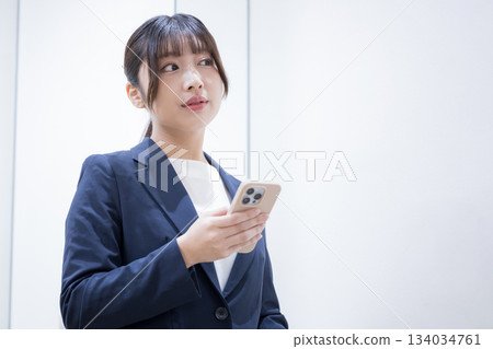 Business woman standing looking at smartphone through glass window, business trip travel and information confirmation scene lifestyle 134034761