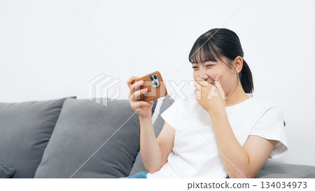 A teenage woman using a smartphone in the living room 134034973