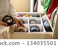 A young beautiful woman puts a convenient order in storing belts in her home wardrobe 134035501