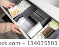 Top view of woman hands neatly organizing bathroom amenities and toiletries in drawer in bathroom. 134035503