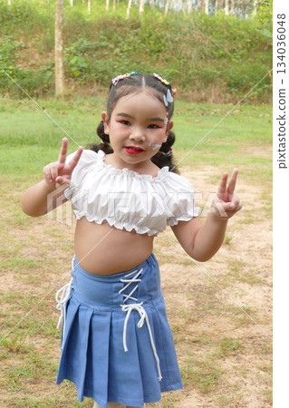 Asian little girl smiling in a vintage dress with red lips and hair style in the park. Asian little girl smiling in a vintage dress with red lips and hair style in the park. 134036048