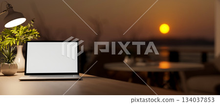 Blank screen laptop and coffee cup on wooden stool table at cafe's rooftop or balcony in the evening Blank screen laptop and coffee cup on wooden stool table at cafe's rooftop or balcony in the evening 134037853