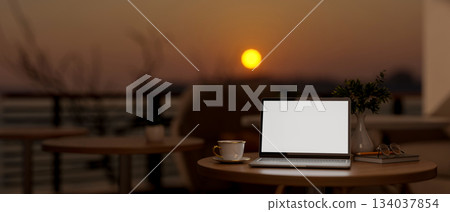 White screen laptop and coffee cup on wooden stool table at cafe's rooftop or balcony in the evening 134037854