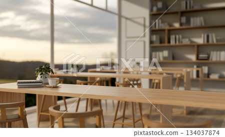 Coffee cup and book on wooden counter or long table on parquet floor in dining hall with glass wall. 134037874
