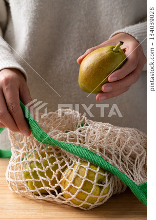 Fresh pear in mesh bag holding by woman hand Fresh pear in mesh bag holding by woman hand 134039028