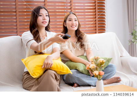 Two young asian woman watching TV together in a cozy living room at home with happy. 134039614