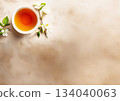 A cup of tea and small flowers on a beige stone table 134040063